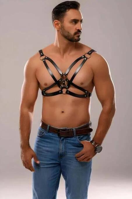 Black faux leather men's chest harness with X-back straps and central silver O-ring worn over bare torso