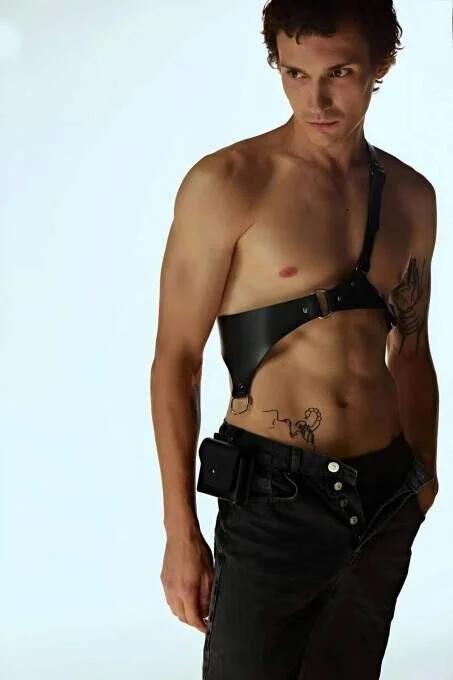 black faux leather asymmetric single-shoulder chest harness with gold O-ring on male model