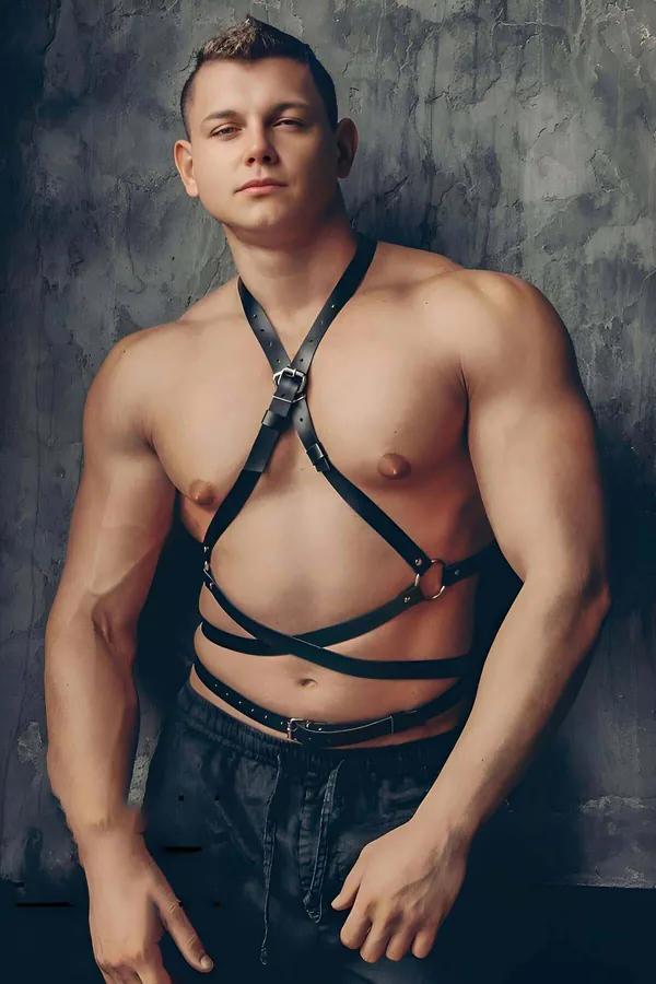 Black faux leather chest and torso body harness with silver buckles and O-ring worn by a male model
