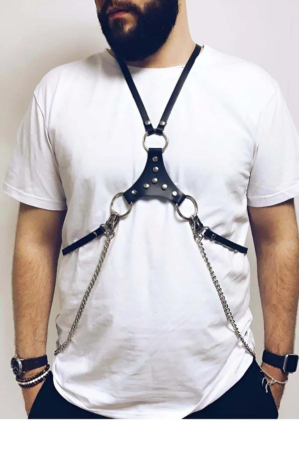 black faux leather chest harness with studded triangle panel three silver O-rings and dangling curb-link chains worn over whi