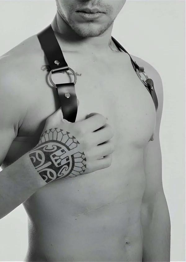 Black vegan leather shoulder harness with silver O-rings and adjustable flat straps on male torso