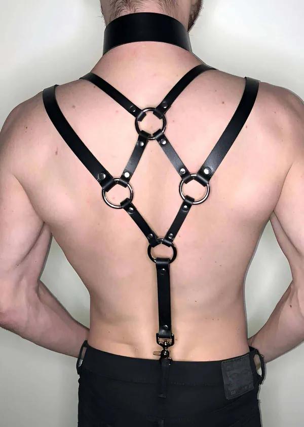 Black faux leather back harness with four silver O-rings and X-cross strap design, worn with matching wide collar