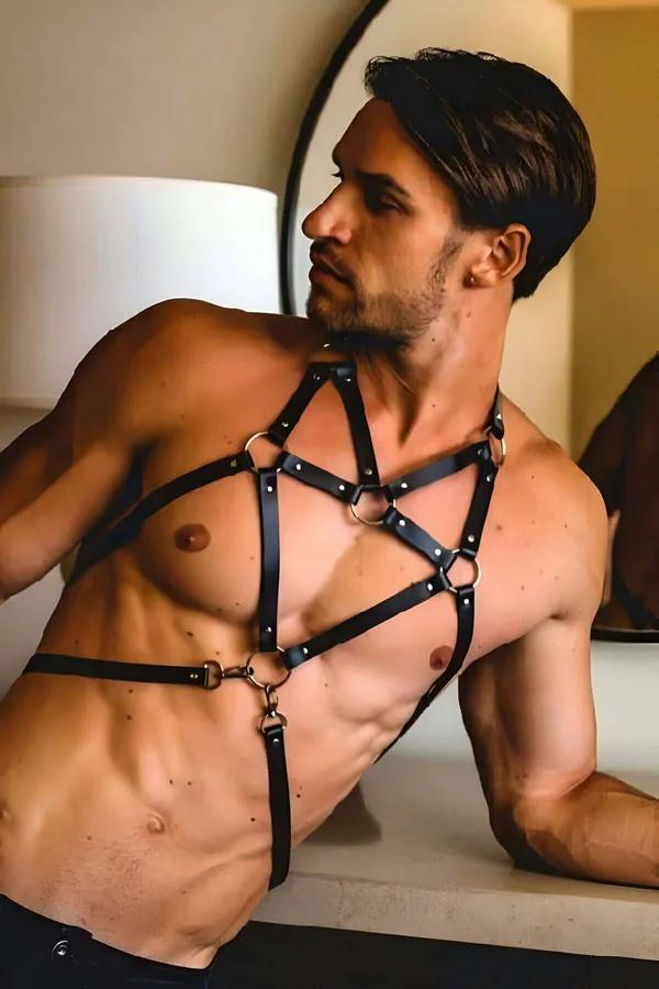 Black faux leather caged chest body harness with four gold O-rings worn by male model, full torso view