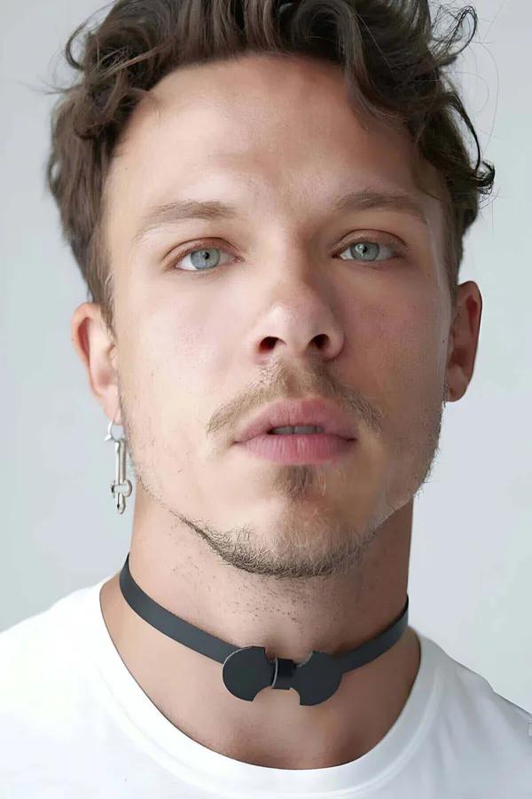 Black faux leather bow tie choker with matte black buckle worn at mid-neck on male model in white T-shirt