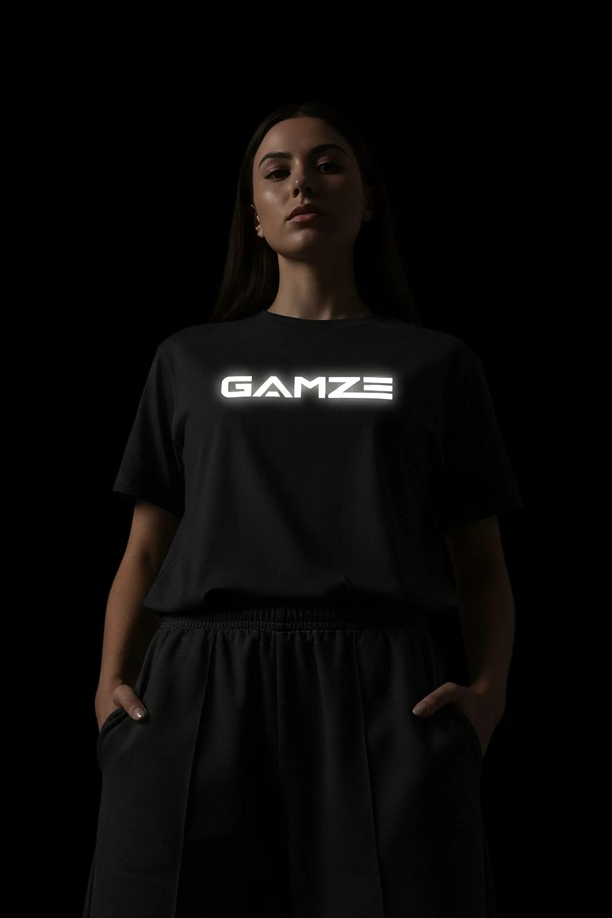black reflective graphic t-shirt with bold custom text glowing bright white on chest in low-light studio shot