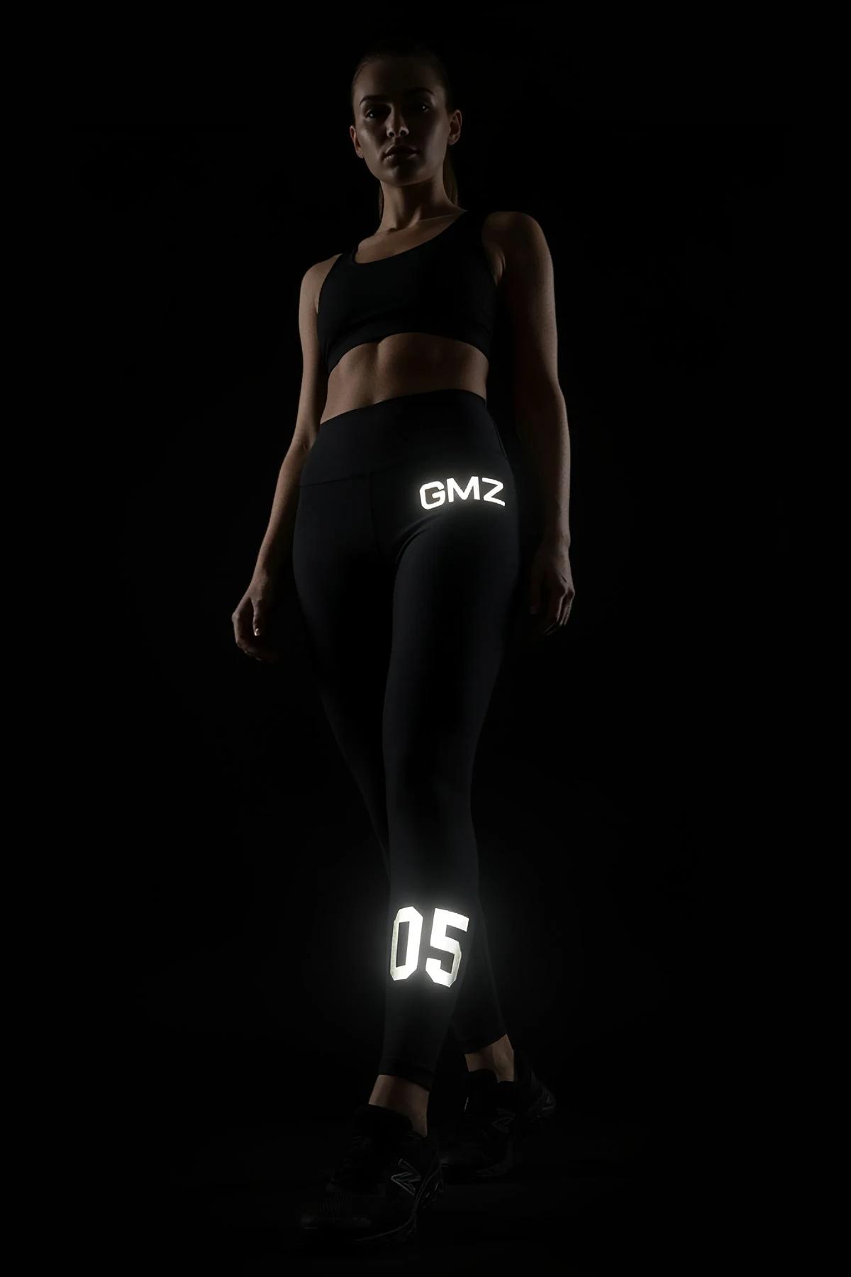 black high-waist performance leggings with white reflective letter print on outer thigh and calf full-length fit