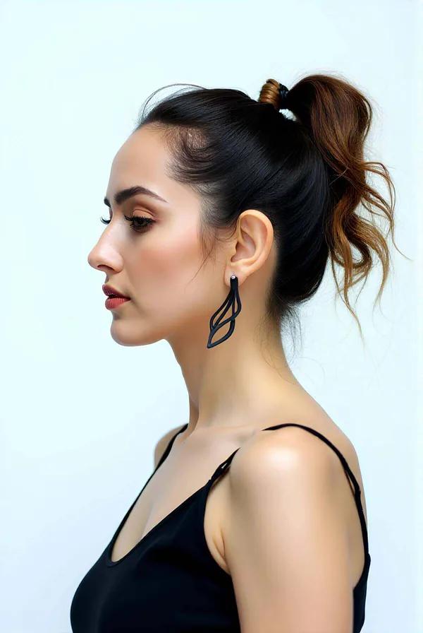 Black matte faux leather laser cut open leaf dangle earrings worn as a single earring showing double-leaf geometric silhouett
