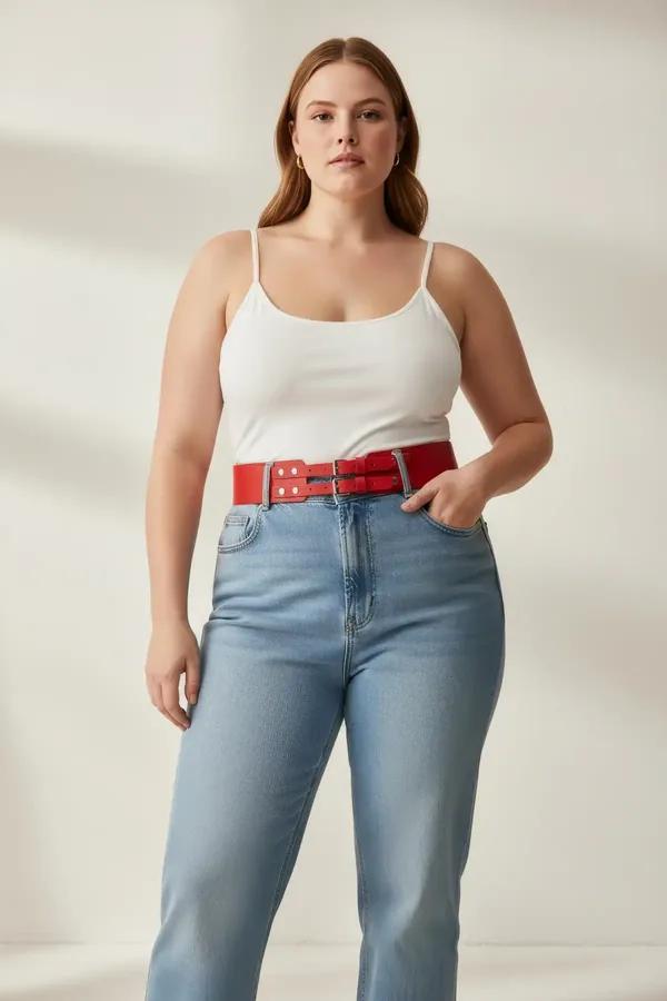 red faux leather wide waist belt with twin silver buckles worn over cream top and beige trousers