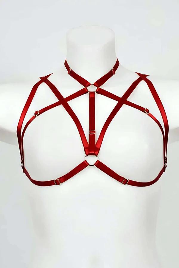 Red strappy chest harness with geometric cross strap pattern and gold-tone central O-ring on white mannequin