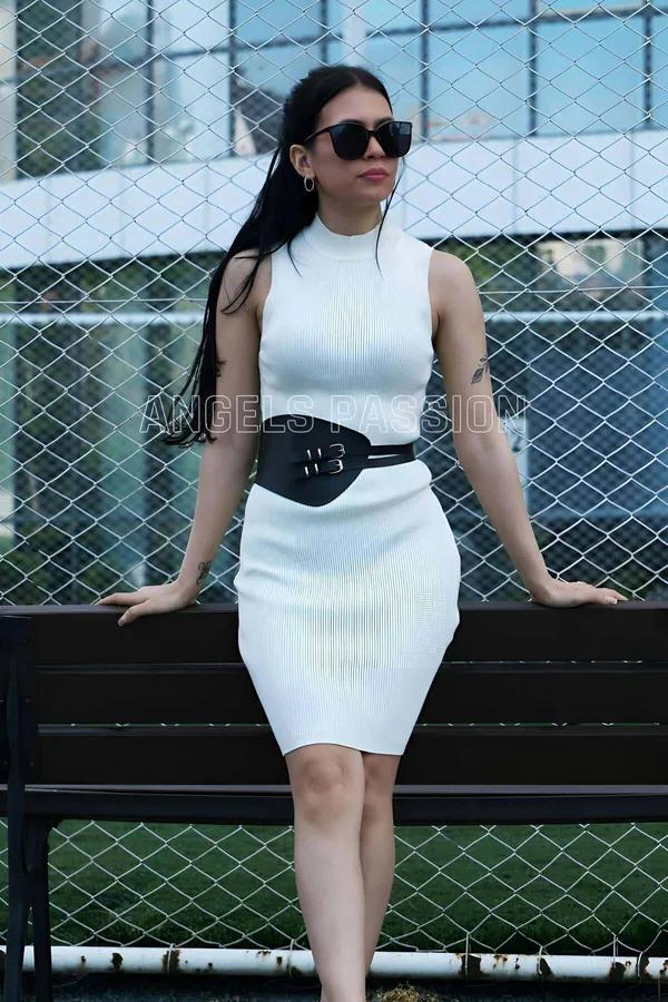 black vegan leather wide waist cincher harness with three silver buckles worn over white ribbed dress