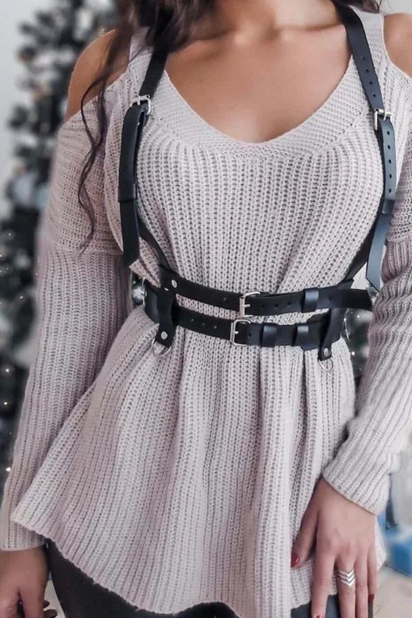 Black faux leather body harness with dual silver buckles worn over a cream ribbed knit sweater