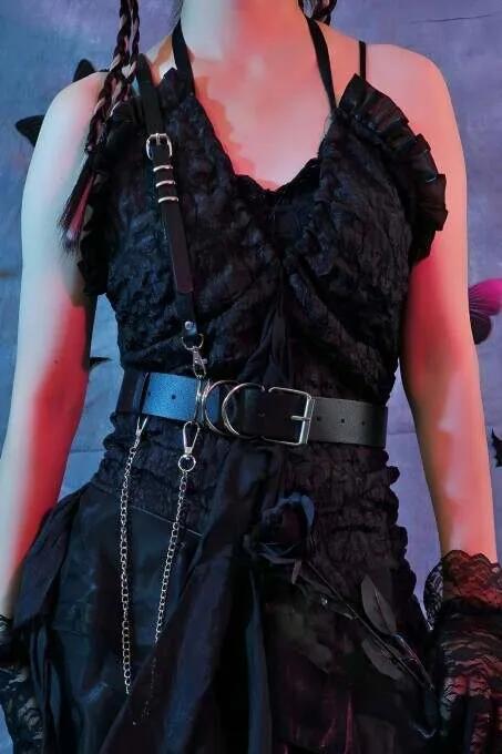 Black faux leather single-shoulder harness with wide waist belt and detachable silver chain drop, worn over dark lace dress