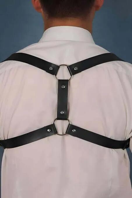 black faux leather back-strap harness with dual silver O-rings and X-strap construction worn over white shirt