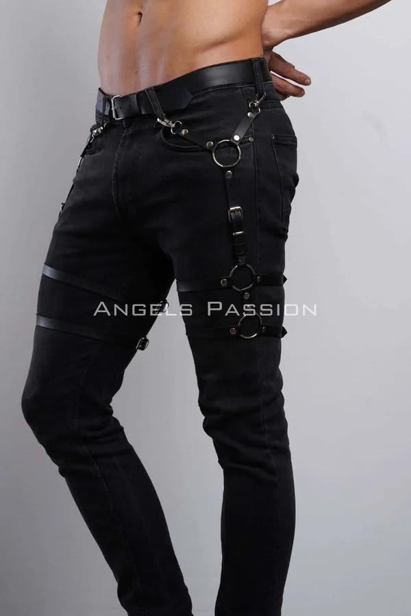 black faux leather leg harness with three silver O-rings worn over black jeans, adjustable buckle straps at hip thigh and kne